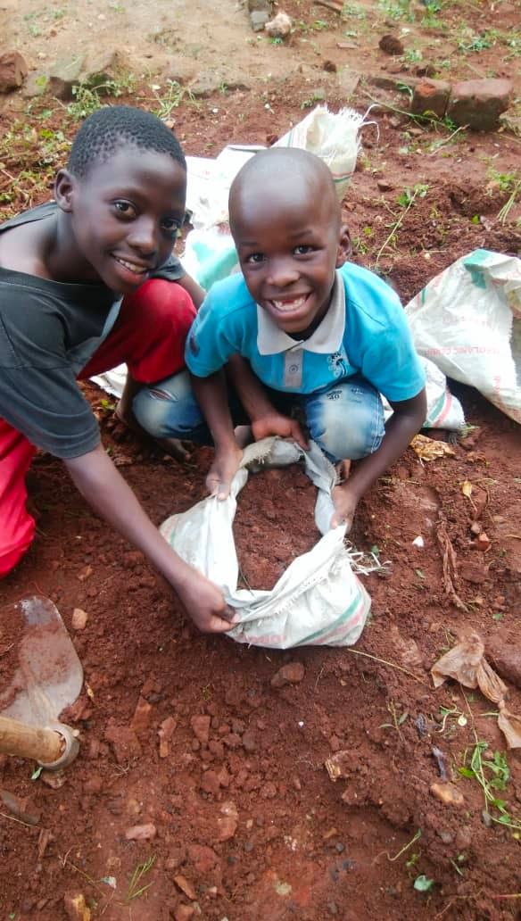 Two of the Desire children planting tomato seedlings in the garden